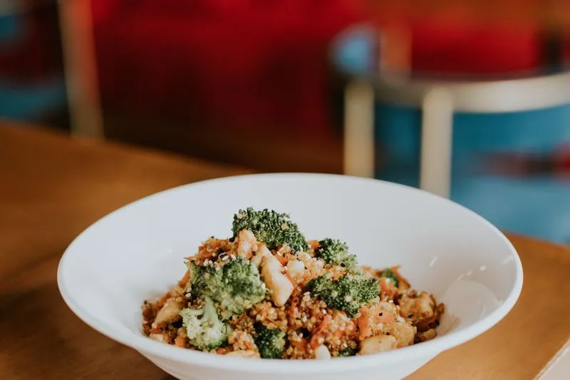 Bol de quinoa au poulet, brocoli, carottes et graines de sésame, servi dans un restaurant