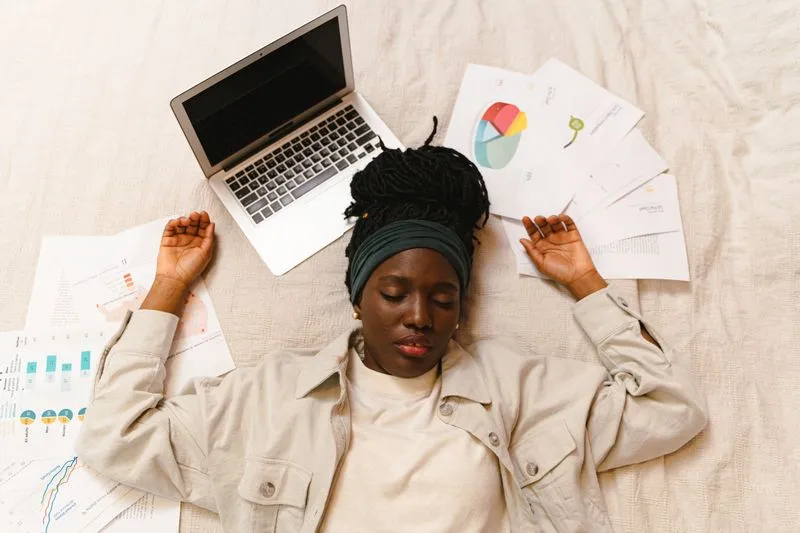 Femme allongée, épuisée, entourée de documents de travail