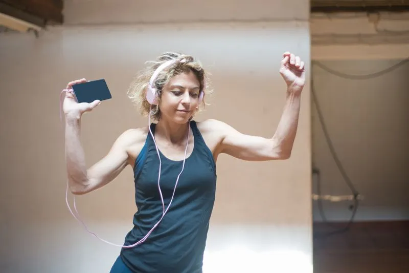 Femme dansant casque sur les oreilles et téléphone à la main