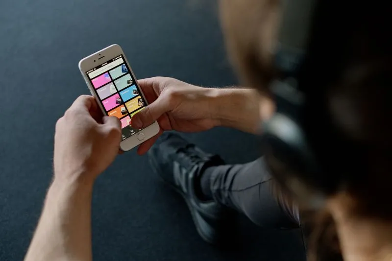 Personne casque sur les oreilles consultant une application de playlists sur son téléphone