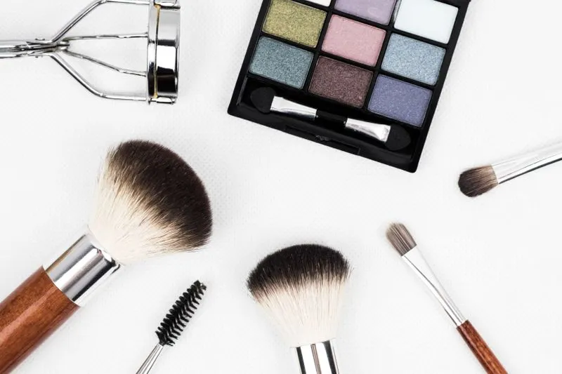Pinceaux, palette de fards et outils professionnels de maquillage, à plat sur fond blanc