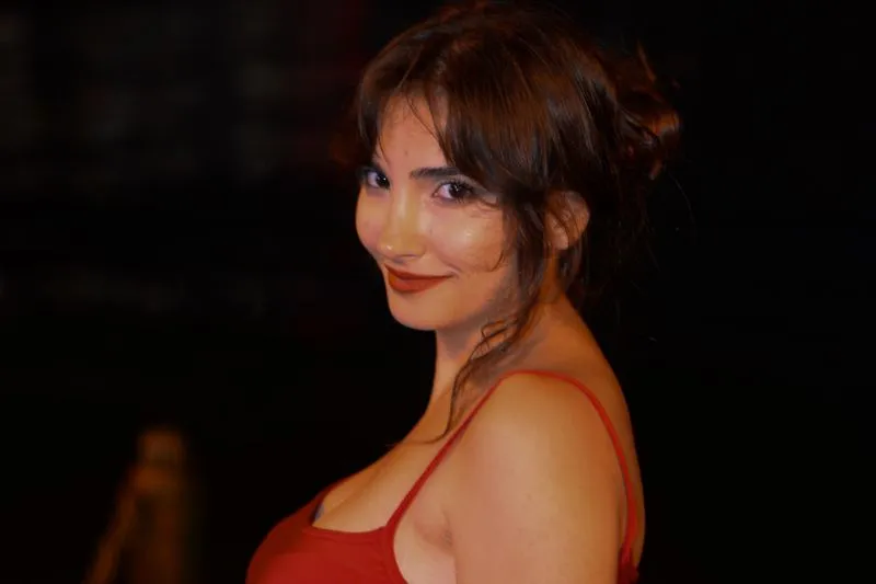 Portrait de femme au rouge à lèvres brique, en haut rouge, sur fond noir de soirée