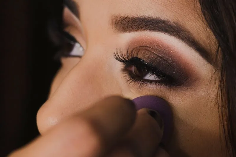 Smoky eye brun doré, éponge de maquillage passée sous l'œil pour nettoyer les retombées