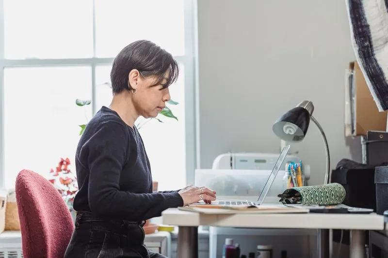 Femme assise à son bureau qui fait une recherche sur un ordinateur portable