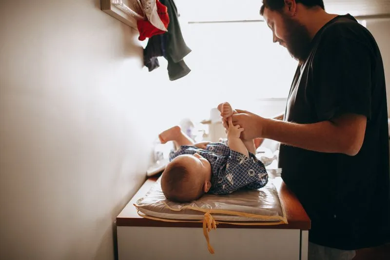 Père changeant la couche de son bébé sur une table à langer