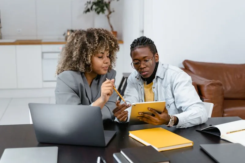 Couple consultant une tablette et des carnets pour organiser la répartition des tâches