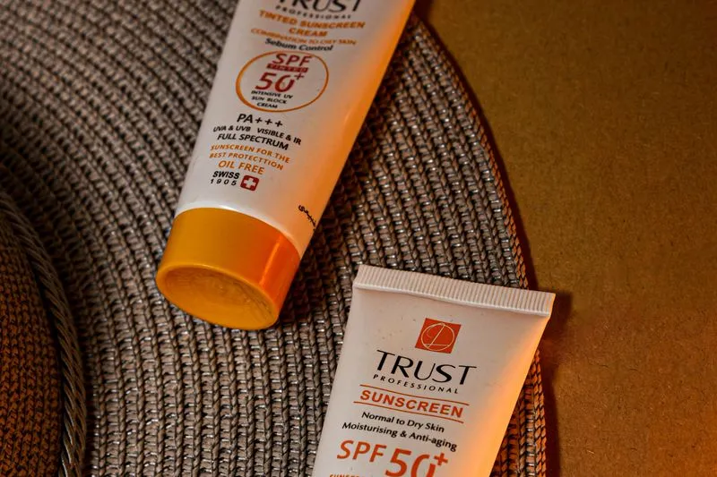 Deux tubes de crème solaire SPF 50+ posés côte à côte sur un set de table tressé
