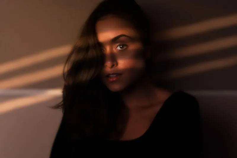 Rayures de lumière et d'ombre traversant un visage dans la pénombre