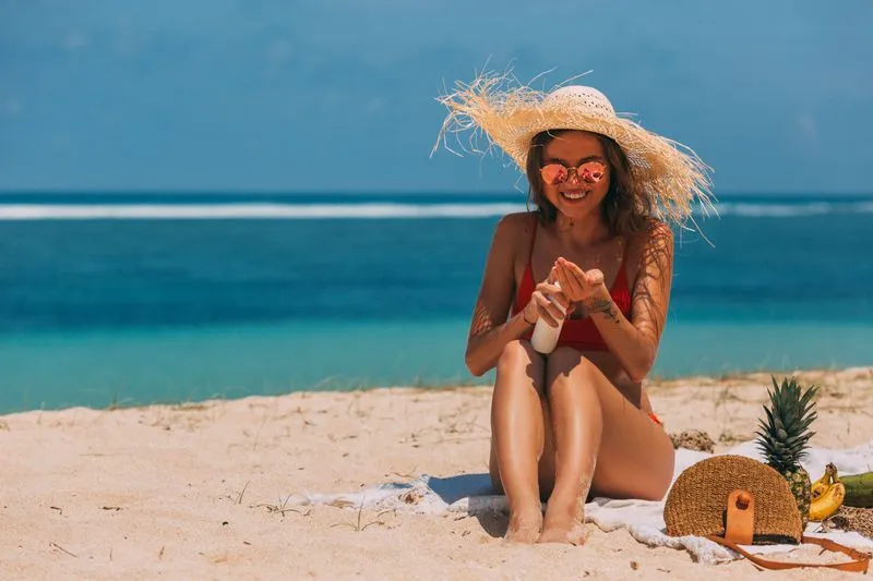 Femme appliquant une crème solaire sur la plage en été