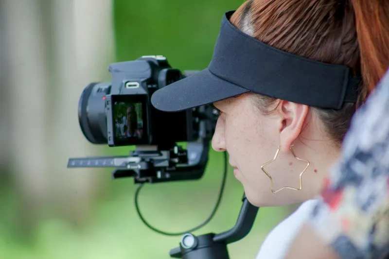 Femme en visière qui filme en extérieur avec une caméra montée sur stabilisateur