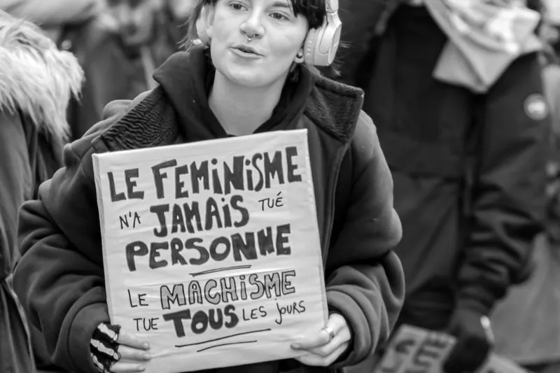 Manifestante tenant une pancarte en carton : « Le féminisme n'a jamais tué personne, le machisme tue tous les jours »