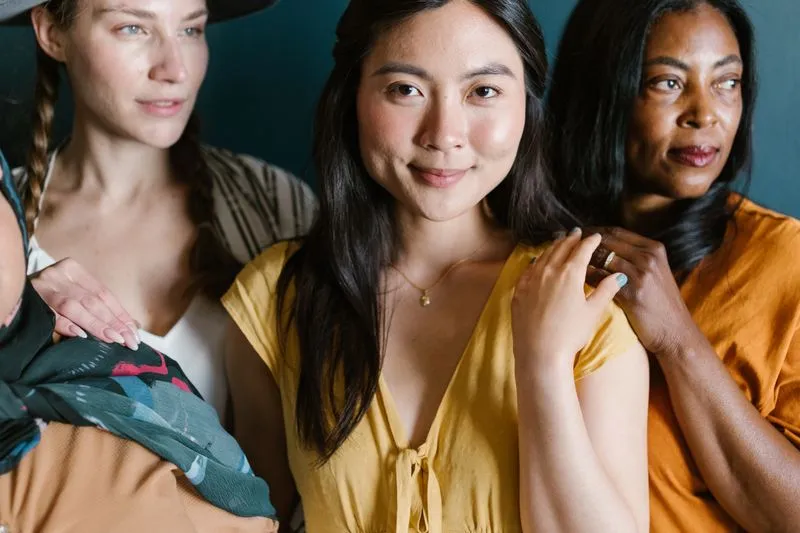 Femmes d'origines différentes serrées les unes contre les autres, une main posée sur l'épaule de leur voisine