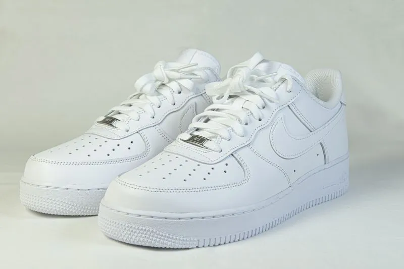 Paire de Nike Air Force 1 basses entièrement blanches sur fond gris clair