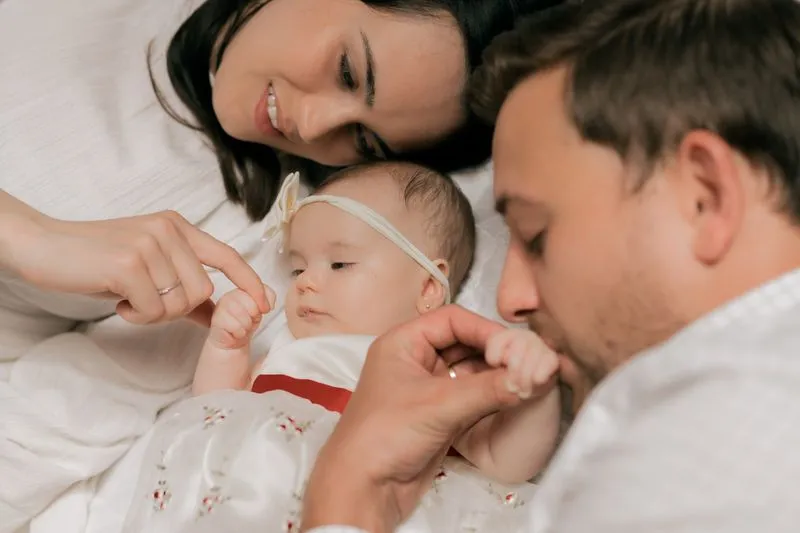 Un couple allongé de part et d'autre de leur bébé, chacun absorbé par lui