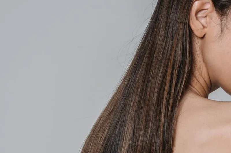 Longs cheveux bruns et lisses tombant sur une épaule nue
