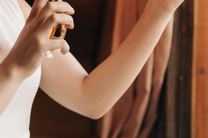 Femme vaporisant un parfum à l'intérieur de son avant-bras