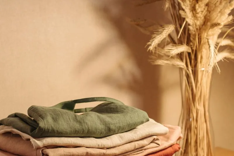 Pile de vêtements pliés dans des tons neutres, kaki et rosé