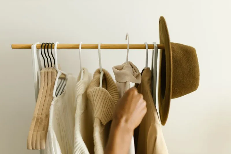 Pulls, cardigan et chapeau aux tons neutres coordonnés sur un portant