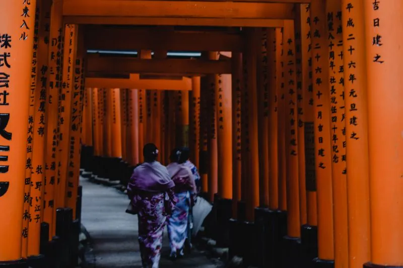 Deux femmes en kimono traversent les torii orange du sanctuaire Fushimi Inari à Kyoto