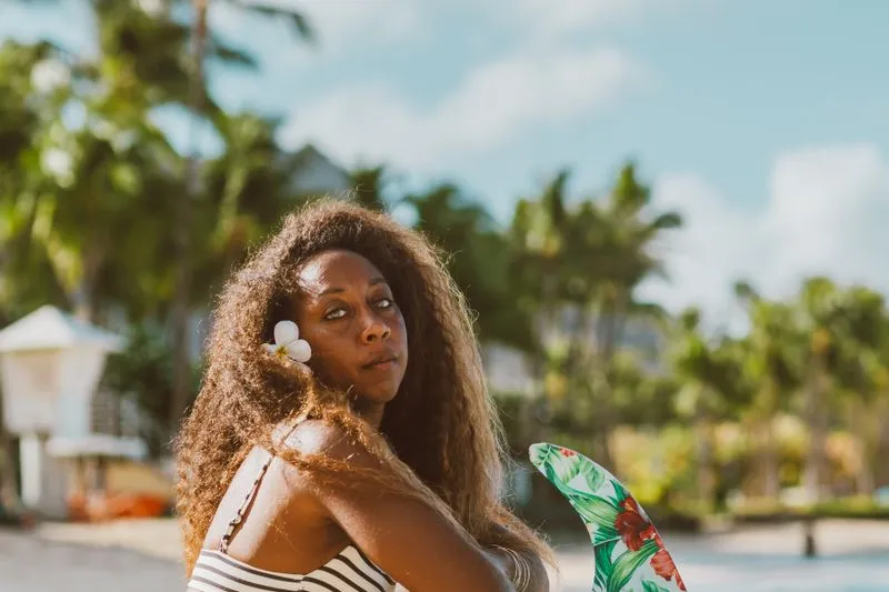 Femme avec une fleur blanche dans les cheveux sur une plage tropicale bordée de palmiers