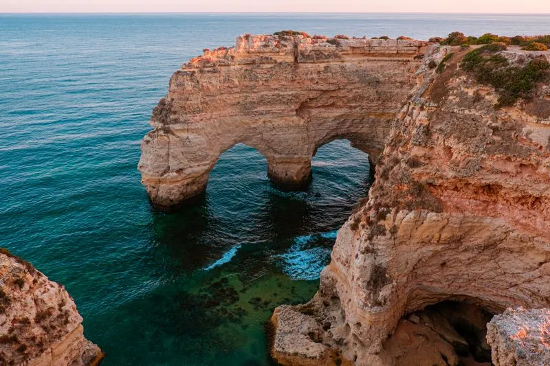 Double arche naturelle dans les falaises dorées de l'Algarve, au-dessus d'une mer turquoise