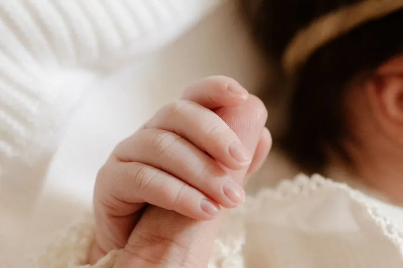 Main d'un nouveau-né serrant le doigt d'un adulte, en gros plan, lumière douce