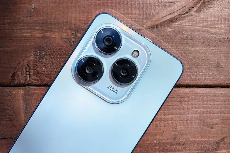 Smartphone bleu clair posé écran contre une table en bois, objectifs photo tournés vers le haut