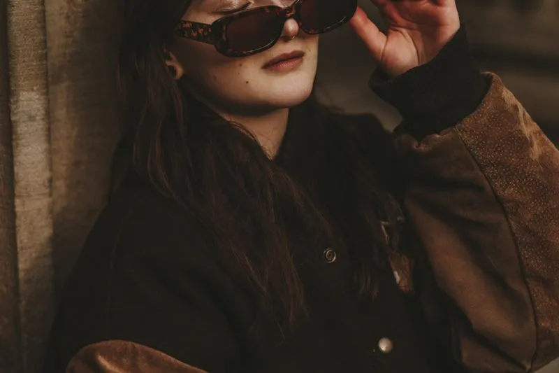 Femme à lunettes de soleil écaille dans un blouson marron chocolat aux manches en daim