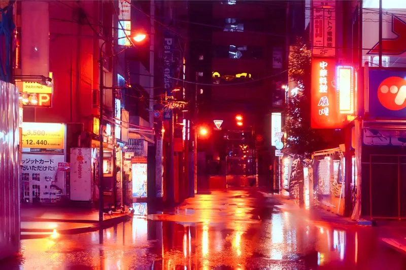 Rue déserte détrempée par la pluie, la nuit, baignée par la lumière rouge des enseignes au néon