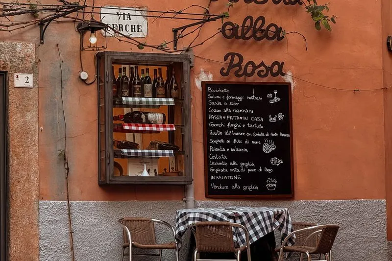 Ardoise de menu écrite à la craie sur la façade d'une osteria italienne, au-dessus d'une table à nappe à carreaux