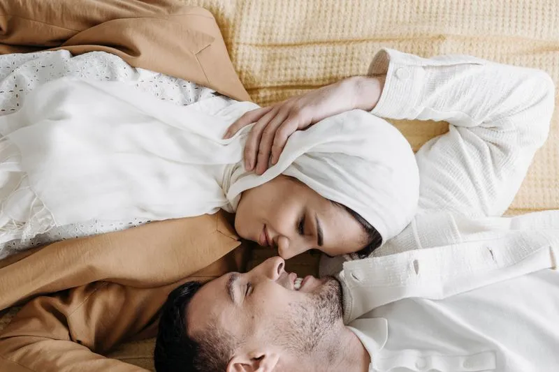 Couple allongé tête contre tête sur un plaid jaune, qui se sourit