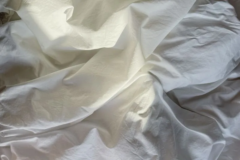 Draps blancs froissés, éclairés par une lumière douce