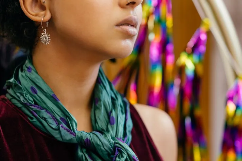 Foulard vert à pois violets noué autour du cou d'une femme en haut de velours bordeaux