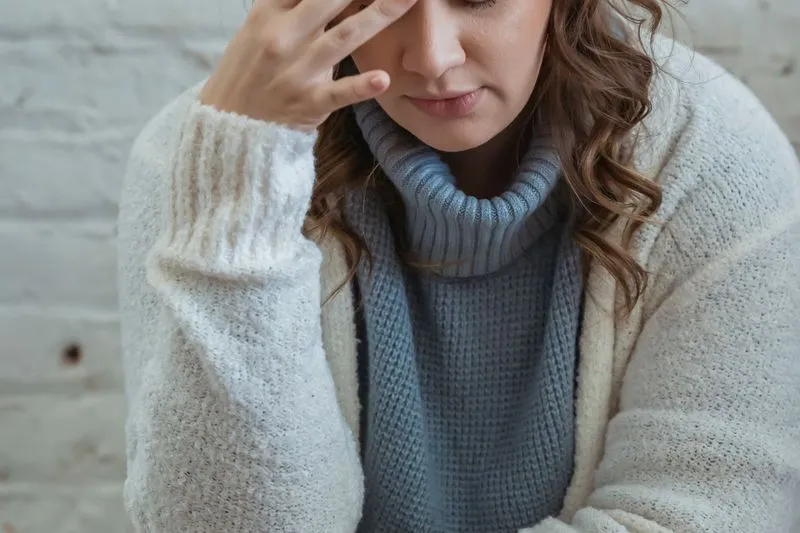 Femme la tête baissée, la main sur le front, qui s'accorde un moment pour souffler
