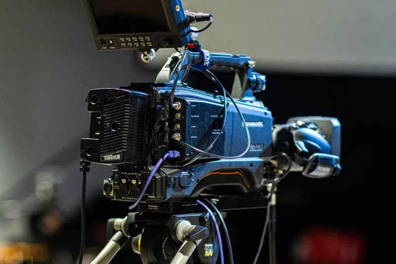 Caméra de télévision professionnelle montée sur trépied, avec son écran de contrôle et ses câbles