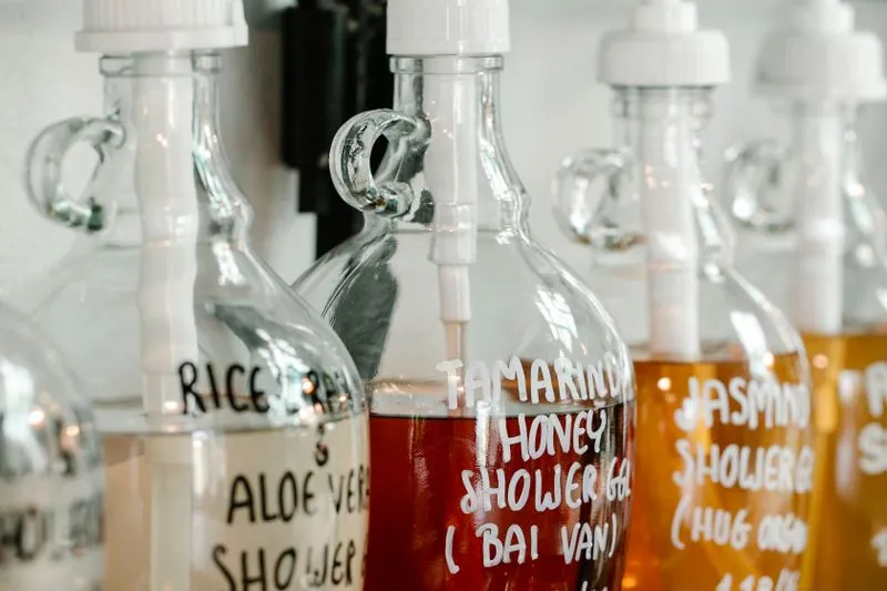 Distributeurs en verre remplis de gels douche au miel, au jasmin et à l'aloe vera, étiquetés à la main