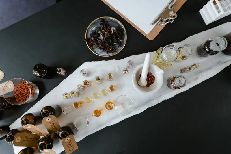 Vue de dessus d'un atelier de parfum : fioles d'essences, flacons étiquetés, mortier et pétales séchés