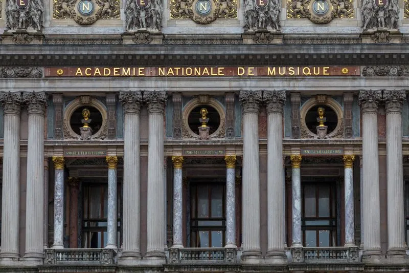 Détail de la façade du Palais Garnier : colonnes de marbre, bustes dorés et inscription « Académie nationale de musique »