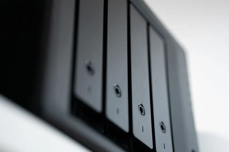Façade d'un NAS noir à quatre baies vue de biais, tiroirs à disques alignés