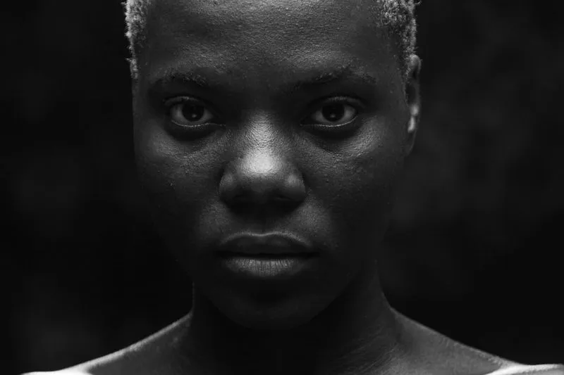 Portrait en noir et blanc, en gros plan, d'une jeune femme noire aux cheveux courts décolorés