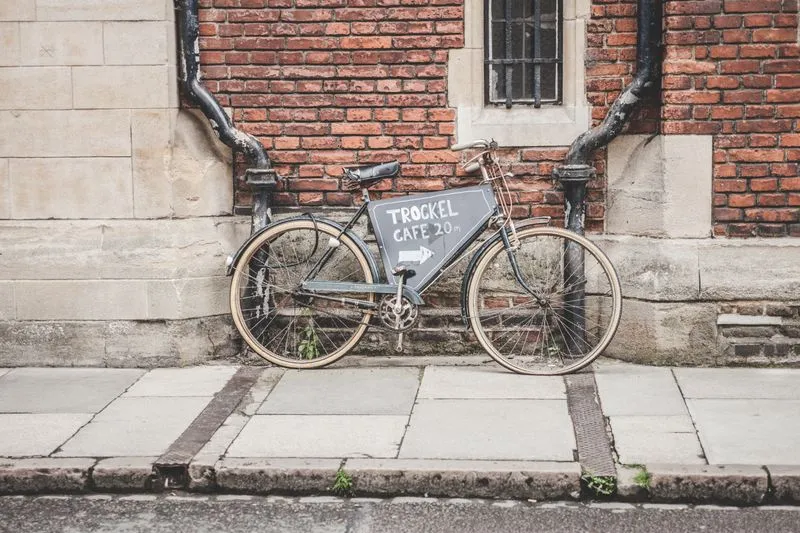 Bicyclette ancienne appuyée contre un mur de briques, une pancarte « Trockel Café 20 m » fixée au cadre