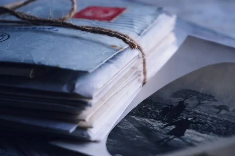 Pile de vieilles enveloppes nouées d'une ficelle, à côté d'une photographie ancienne en noir et blanc