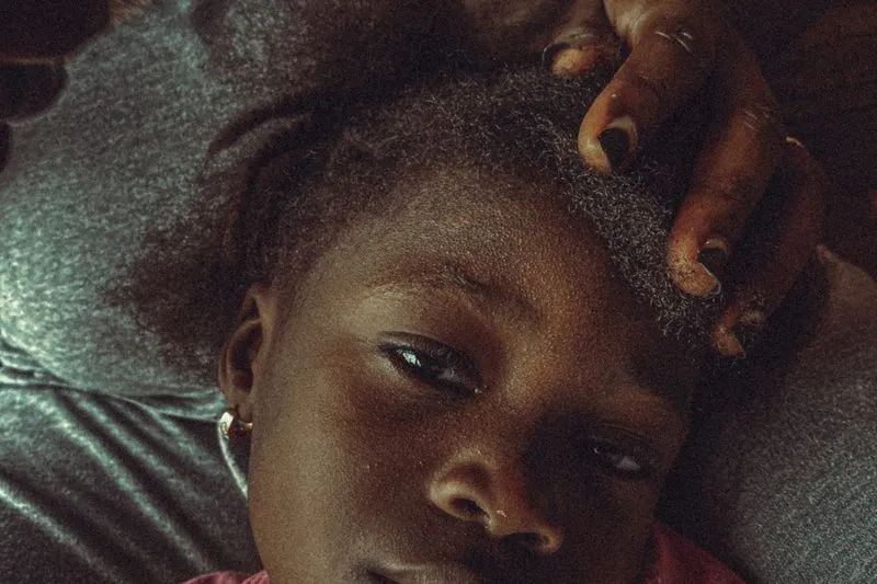 Main d'adulte qui écarte doucement les cheveux d'une petite fille près du sommet du crâne