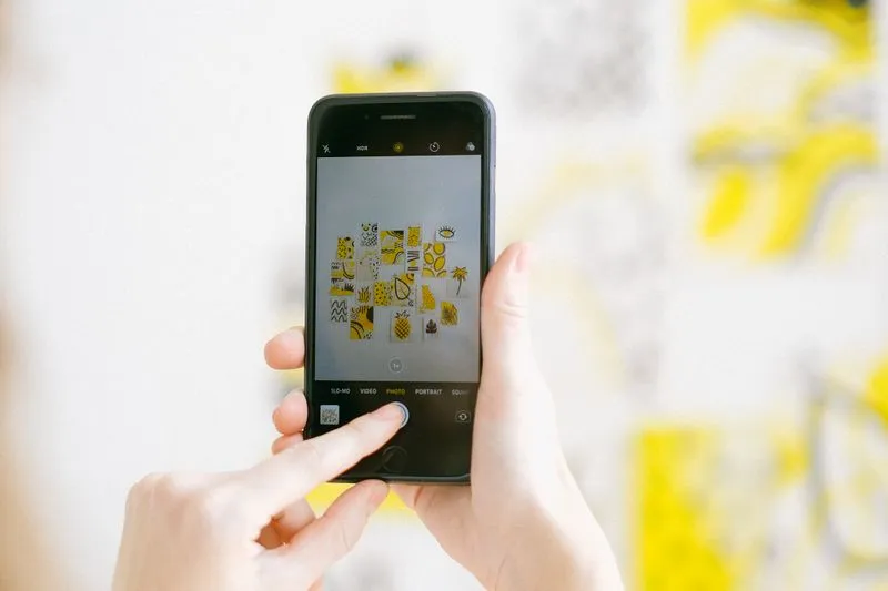 Gros plan sur des mains qui photographient un mur avec un smartphone, l'application photo ouverte à l'écran