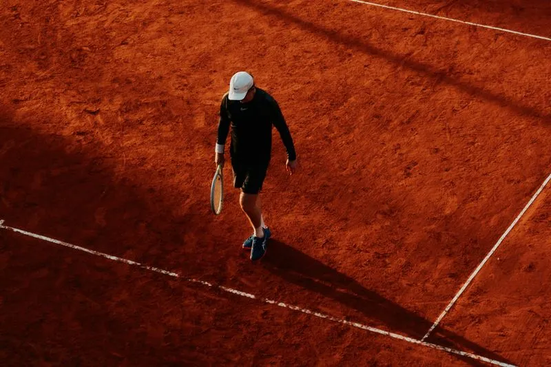 Joueur de tennis vu d'en haut qui se déplace sur un court en terre battue orange