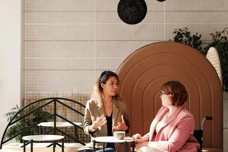 Deux jeunes femmes qui discutent avec animation autour d'une tasse de café