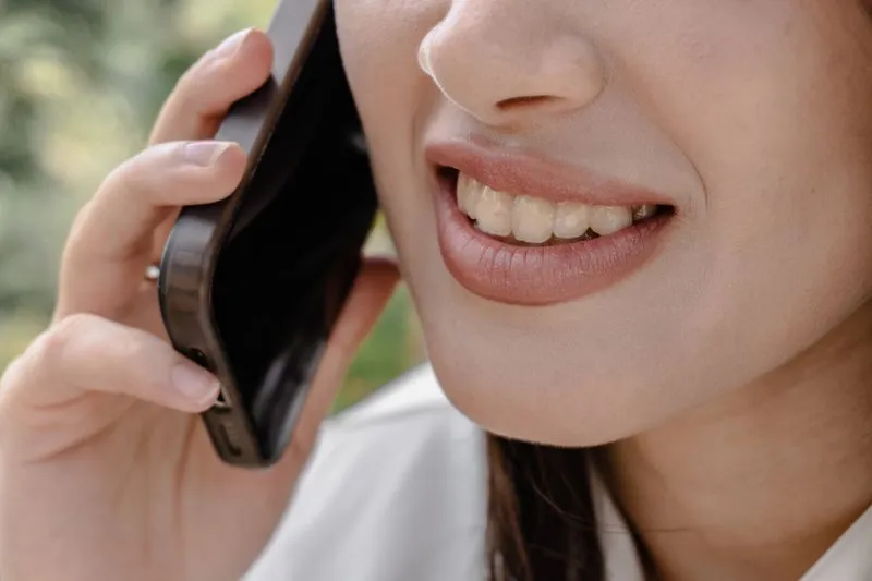 Gros plan sur le sourire d'une jeune femme qui rit au téléphone