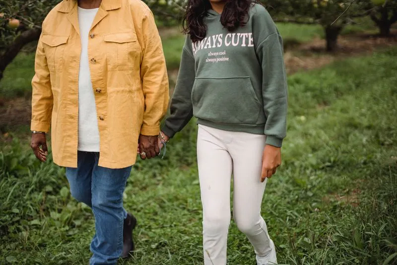 Mère et adolescente marchant main dans la main dans un chemin verdoyant