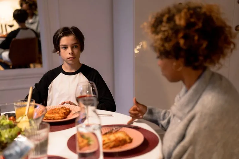 Mère et fils adolescent attablés pour le dîner, en pleine discussion