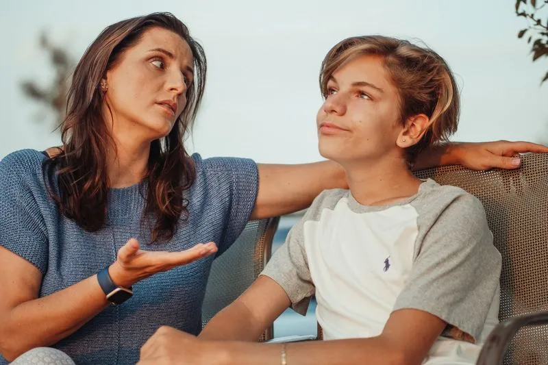 Mère et fils adolescent assis l'un à côté de l'autre, en pleine conversation